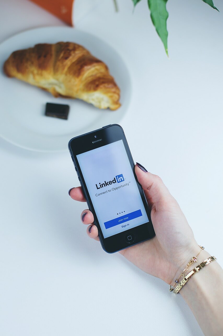 LinkedIn explained; a woman holds a mobile phone with the LinkedIn app login page open.