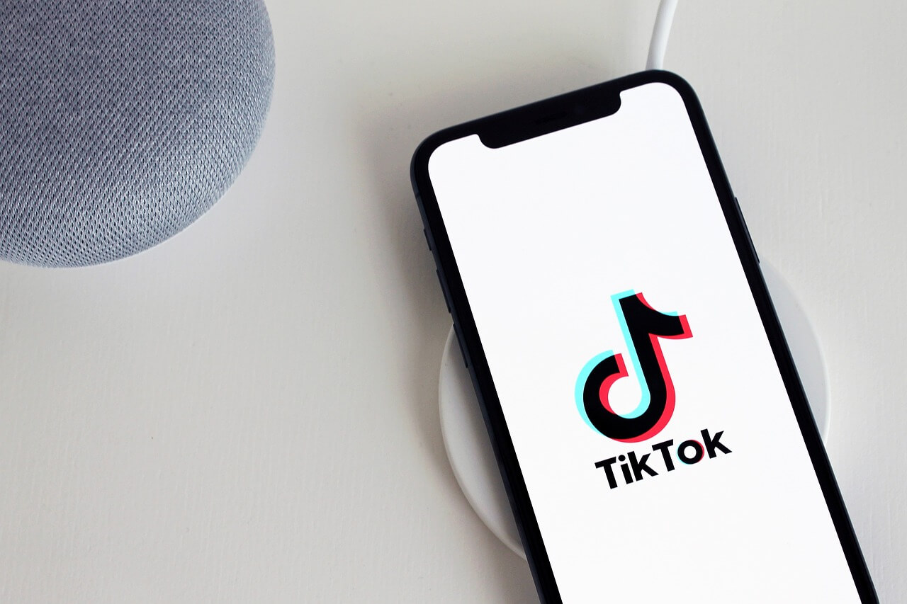 How to get analytics on TikTok; a mobile phone charging with the TikTok app open, showcasing the company logo.